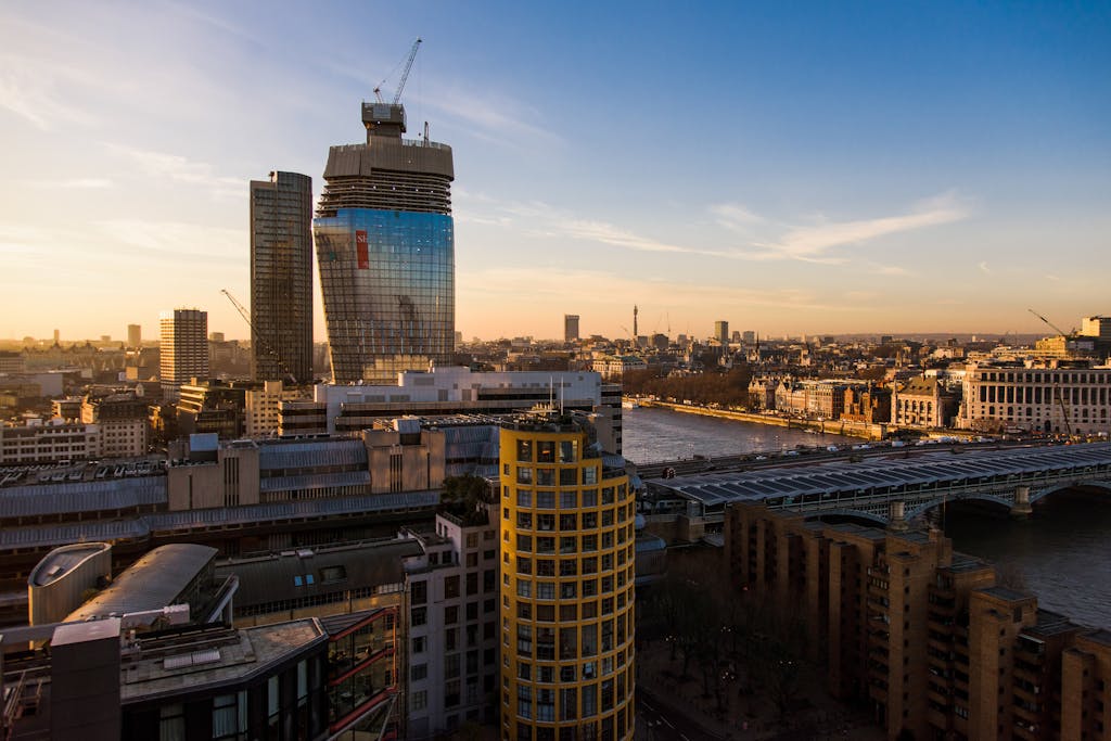 About Synel UK 1 Contemporary multistory financial buildings and residential houses located on streets near calm river with bridge in London city in evening time
